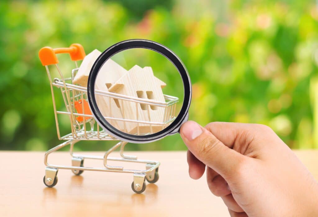 A person holding a magnifying glass over a shopping cart.