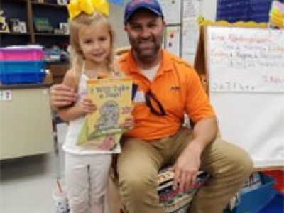 A man and girl holding up a book.